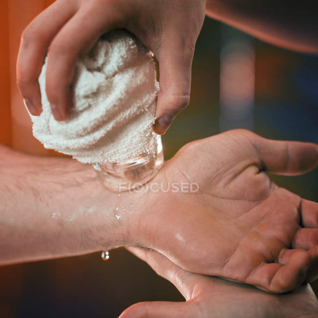Close-up of female physiotherapist performing cryo massage for wrist pain of male athlete. — Stock Photo