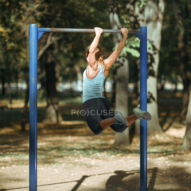 Frau turnt im Park am Reck. — Stockfoto