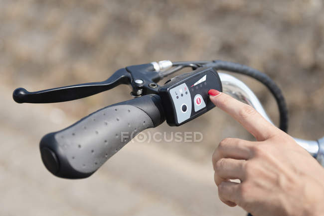 Female hand turning on electric bicycle, close-up. — Stock Photo