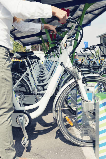 Жінка-комісарка бере електричний велосипед зі станції спільного використання велосипедів . — стокове фото