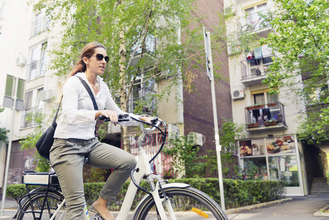 Feminino e-bike viajante andando pela cidade . — Fotografia de Stock