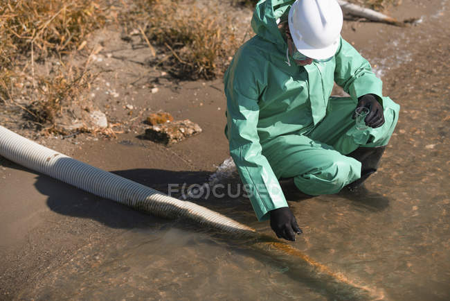 Inspector de calidad del agua toma muestra de agua en el sitio de sospecha de contaminación - foto de stock
