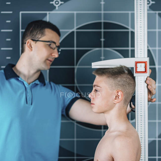 Physiothérapeute mesurant la hauteur de l'adolescent garçon . — Photo de stock