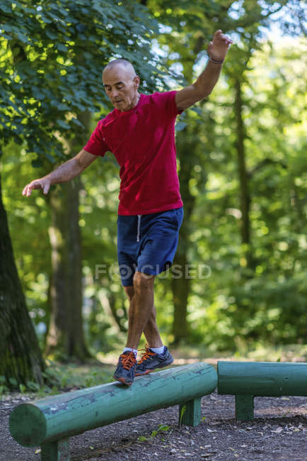 Fit senior man exercising on log in green park. — Stock Photo