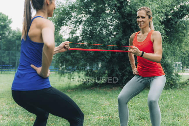 Жінки-друзі тренування з гумкою в літньому парку. — стокове фото
