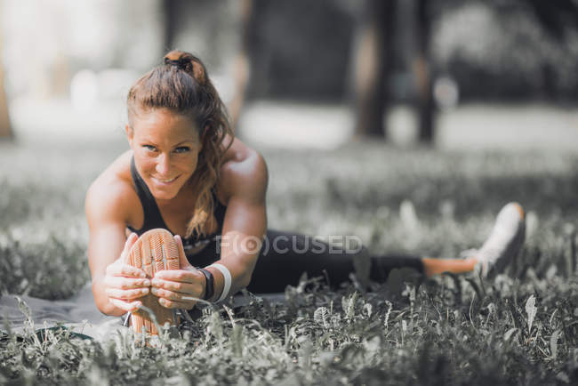 Atleta feminina que se estende após o exercício no parque . — Fotografia de Stock