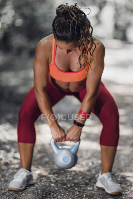 Fit woman exercising with kettlebell in park. — Stock Photo