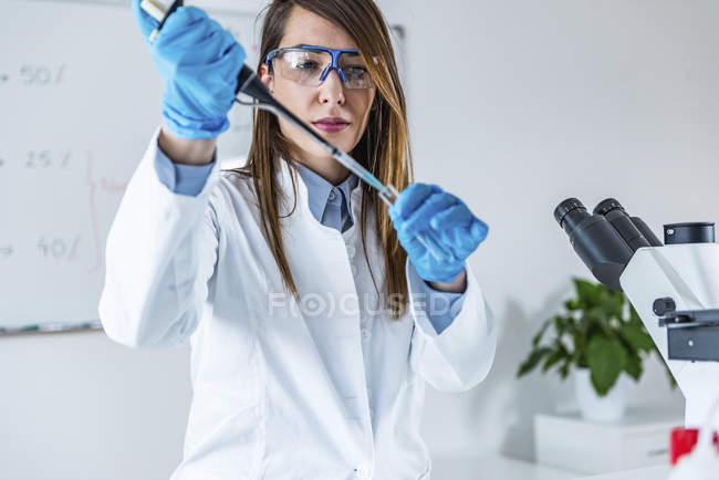 Laboratorio tecnico femminile con micropipetta scientifica . — Foto stock