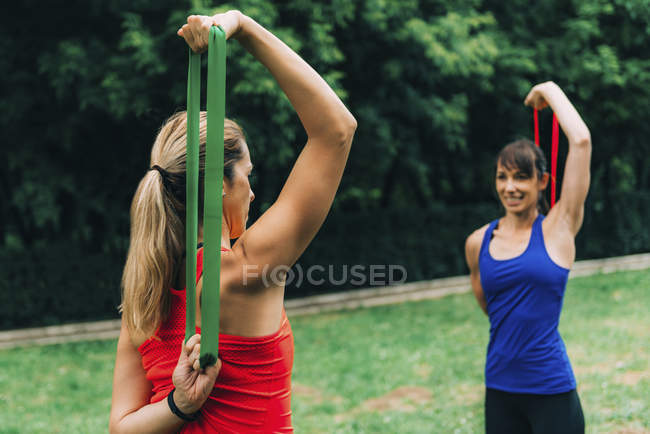 Donne che si allenano con elastici nel parco verde
. — Foto stock