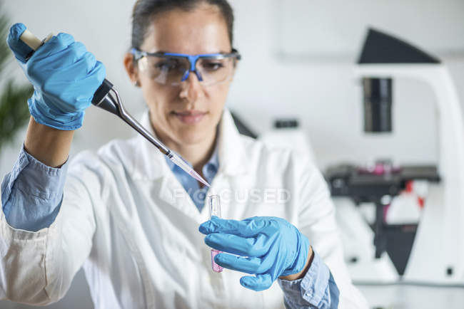Laboratory technician with micro pipette sampling into test tube. — Stock Photo