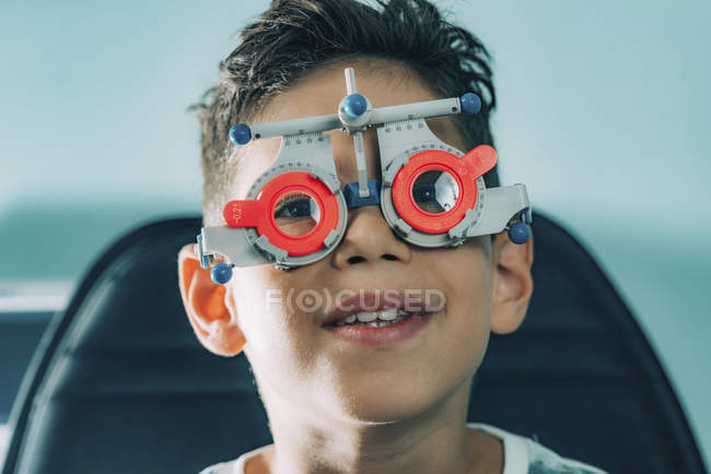 Elementary age boy in ophthalmology glasses while eye examination in clinic. — Stock Photo