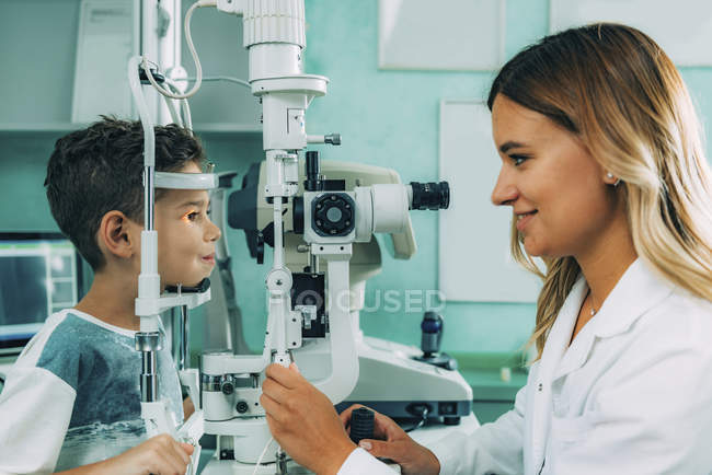Ophthalmologist examining boy eyes with slit lamp in clinic. — Stock Photo