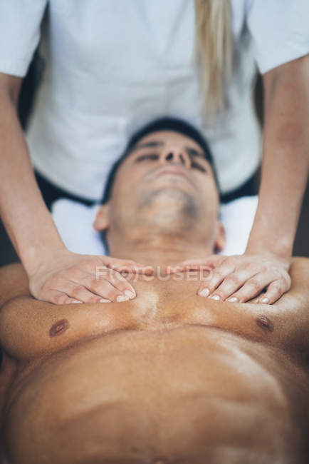 Physiotherapeut massiert jungen Mann Brust. — Stockfoto