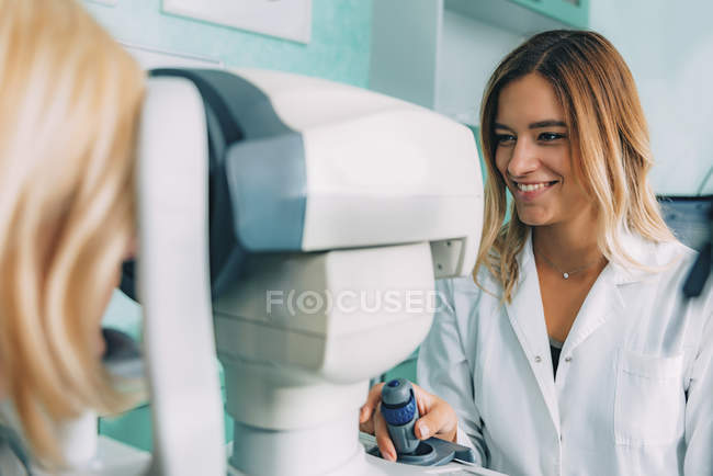 Жіночий пацієнт, який проходить огляд очей авторефрактометра в офтальмологічній клініці . — стокове фото