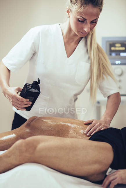 Physical therapist massaging man and applying massage oil. — Stock Photo