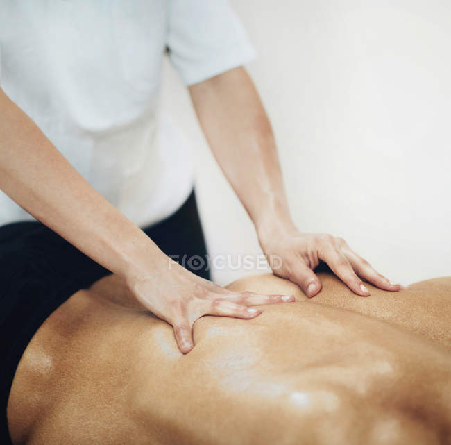 Fisioterapista massaggiare schiena maschile . — Foto stock