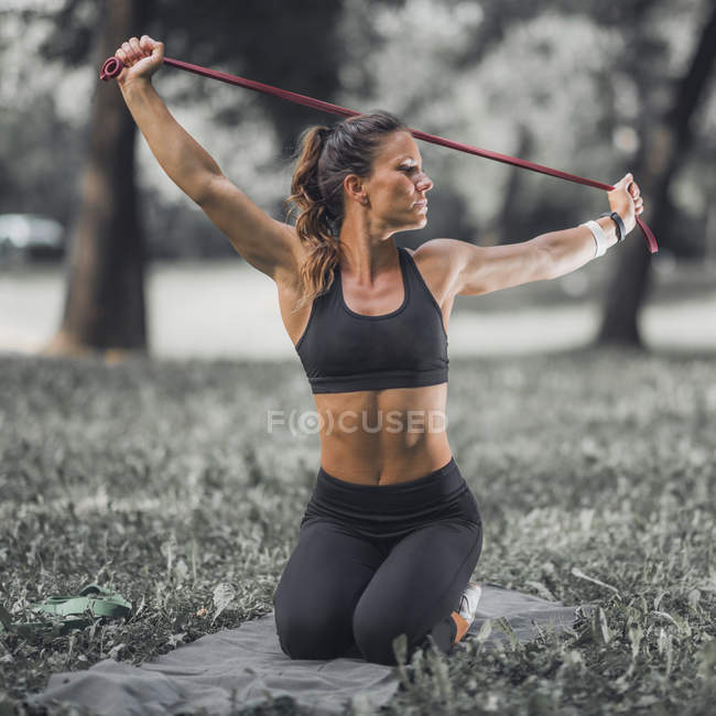Спортсменка розтягується еластичною смугою після фізичних вправ у парку . — стокове фото