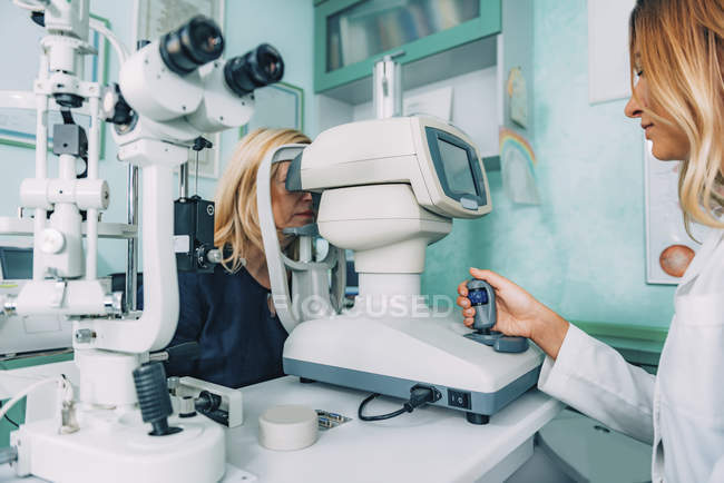 Paciente femenina sometida a autorefractómetro examen ocular en clínica oftalmológica . - foto de stock