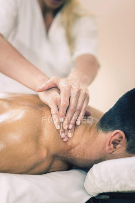 Fisioterapeuta masajeando cuello masculino . - foto de stock
