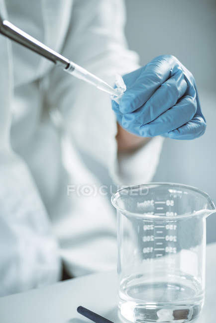 Primer plano de la mano de la muestra de pipeteo de microbióloga femenina en laboratorio
. - foto de stock