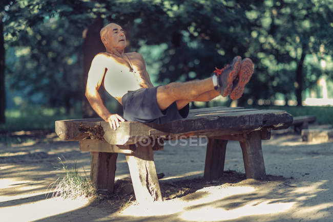 Ajuste o homem sênior que exercita no equipamento de madeira no parque . — Fotografia de Stock