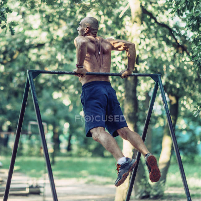 Fit senior man exercising at horizontal bar in park. — Stock Photo