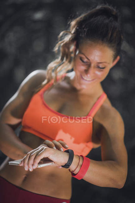 Frau überprüft Fortschritte auf Smartwatch nach Training im Freien. — Stockfoto