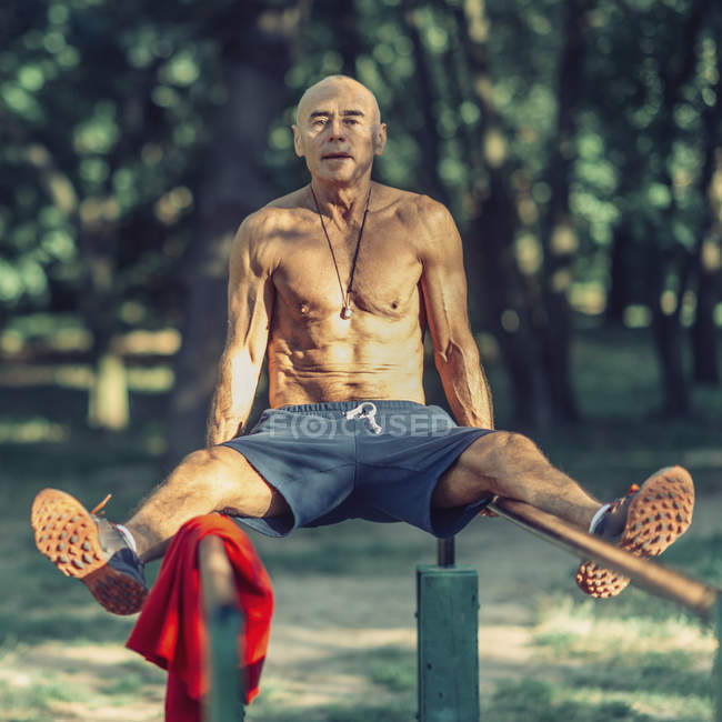Fit senior man exercising on bars in public park. — Stock Photo