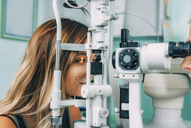 Augenärztin untersucht Patientin mit Spaltlampe in Klinik. — Stockfoto