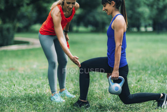 Las mujeres haciendo ejercicio con kettlebell en el parque al aire libre . - foto de stock