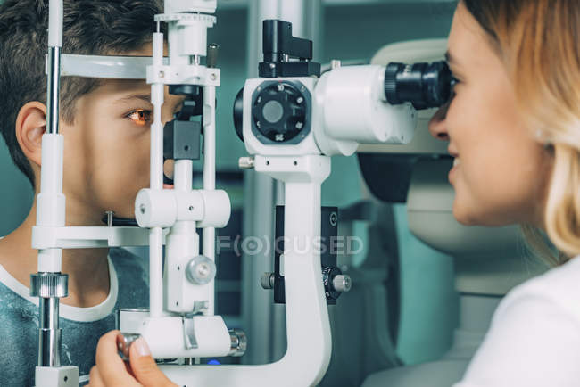 Menino da idade elementar submetido a exame visual com lâmpada de fenda na clínica de oftalmologia . — Fotografia de Stock