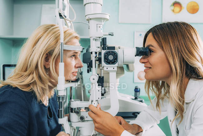 Ophthalmologist examining female patient with slit lamp in clinic. — Stock Photo
