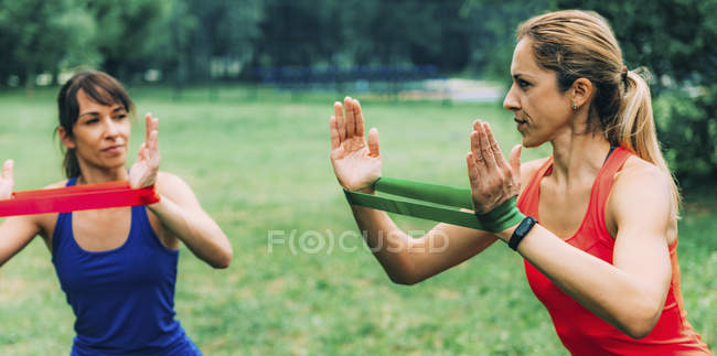 Mulheres exercitando com bandas elásticas no parque verde . — Fotografia de Stock