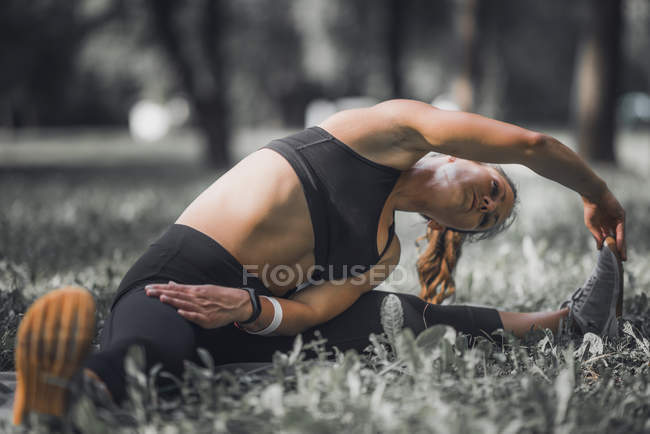 Athlète féminine s'étirant après l'exercice dans le parc . — Photo de stock