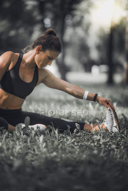 Athletic woman stretching legs after exercise in park. — Stock Photo