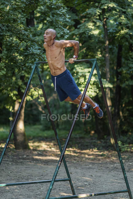 Fitter Senior trainiert am Barren im Park. — Stockfoto