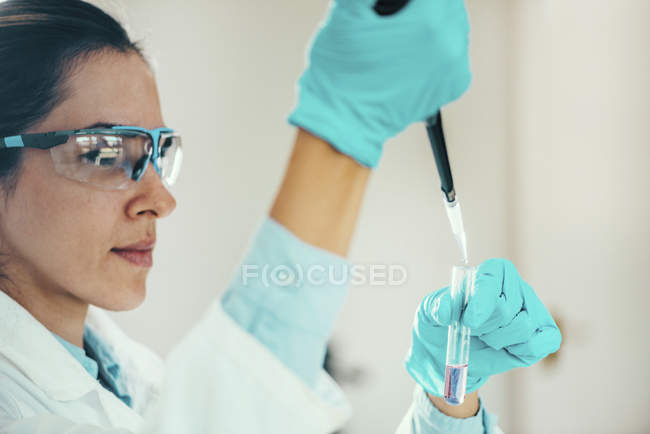 Female researcher with micro pipette sampling into test tube. — Stock Photo