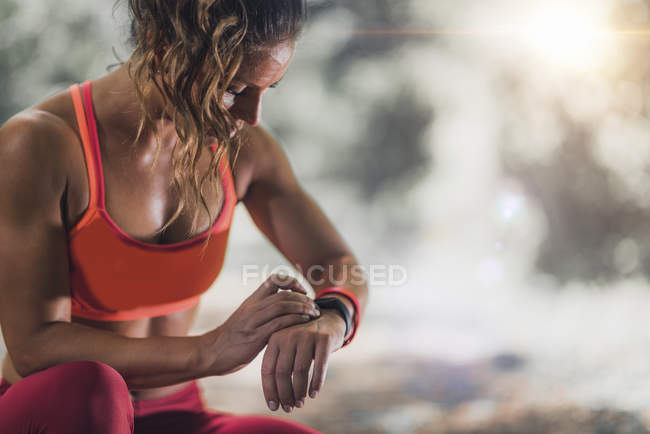 Athlète féminine utilisant une bande de fitness pour suivre l'activité à l'extérieur . — Photo de stock