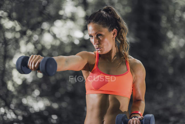Female athlete exercising with dumbbells in park. — Stock Photo