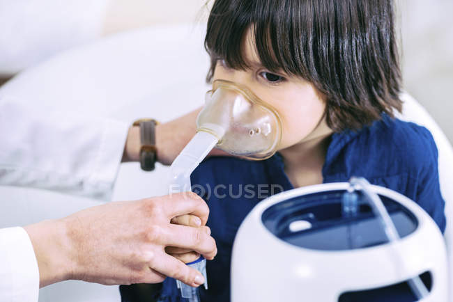 Preschooler boy using inhaler mask with help of female nurse. — Stock Photo