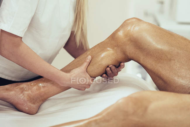 Фізіотерапевт масажує самців спортсменів телят . — стокове фото