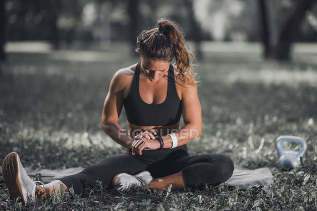 Жінка перевіряє прогрес на смарт-годиннику після тренування на відкритому повітрі . — стокове фото