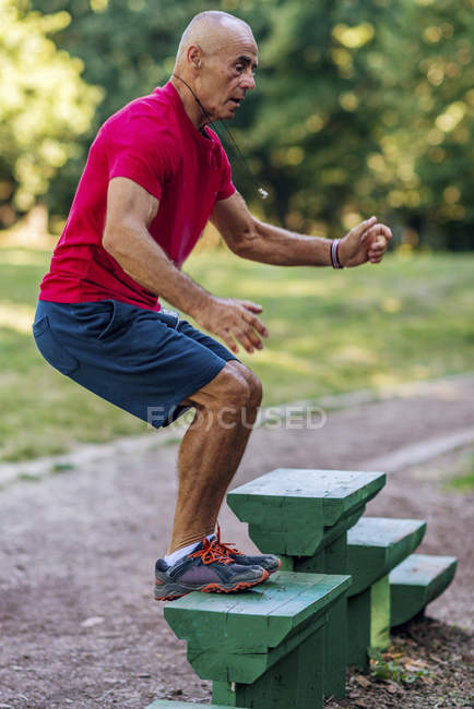 Fit senior man exercising on steps in summer park. — Stock Photo