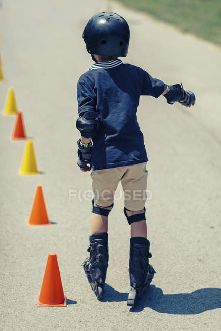 Rear view of boy practicing rollerskating on class in park. — Stock Photo