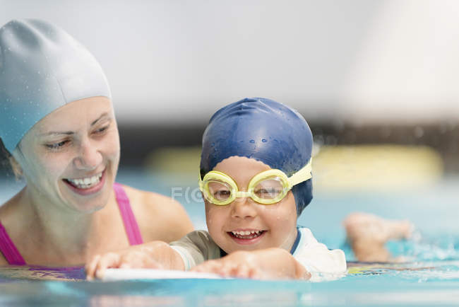 Happy little boy in swimming class with instructor in public pool. — Stock Photo