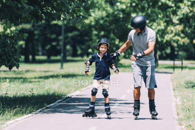 Grand-père enseignant le patinage à roulettes petit-fils dans le parc d'été . — Photo de stock