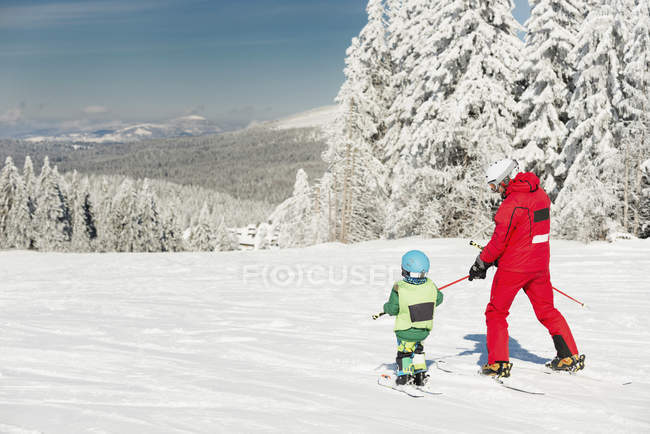 Мальчик-дошкольник катается на лыжах с мужчиной-инструктором . — стоковое фото
