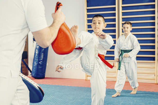 Menino chutando saco de perfuração na classe taekwondo . — Fotografia de Stock