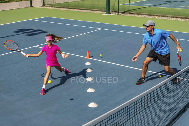 Entrenamiento de jugador de tenis adolescente con entrenador masculino en pista de tenis . - foto de stock