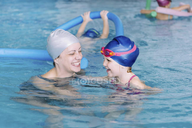 Schwimmlehrerin mit glücklichem kleinen Mädchen im Schwimmbad. — Stockfoto